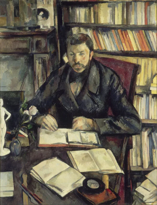 Paul Cézanne – Ritratto di Gustave Geffroy. Un uomo con i baffi siede a un tavolo davanti a una parete di scaffali di libri, le mani unite sopra un libro aperto, a sinistra una statuetta bianca in gesso e un fiore bianco in un vaso blu, Paul Cézanne, 1895–1896, quadro a olio su tela