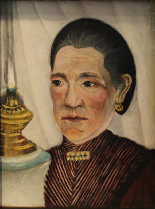 Ritratto della seconda moglie dell’artista, Henri Rousseau – una donna anziana dai capelli scuri e abito a righe davanti a una tenda più chiara, a sinistra una lampada a olio dorata accesa